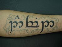 TATUAJE LETRAS ELFICAS Y ADORNOS EN ANTEBRAZO